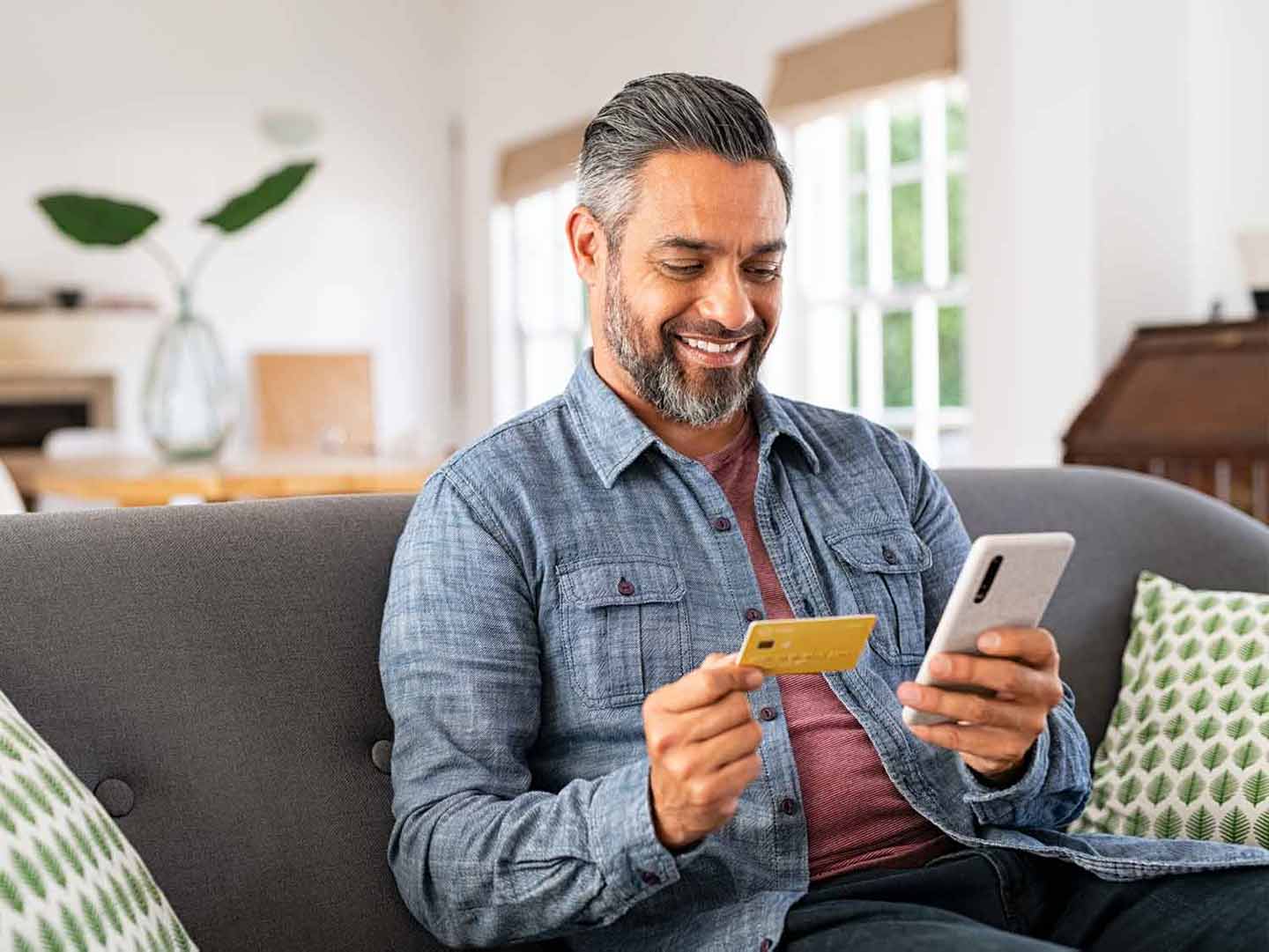 smiling man paying online with a credit card and mobile phone