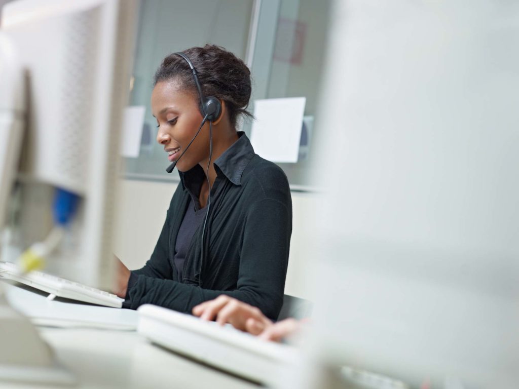 contact center agent sitting at desk and talking on the phone