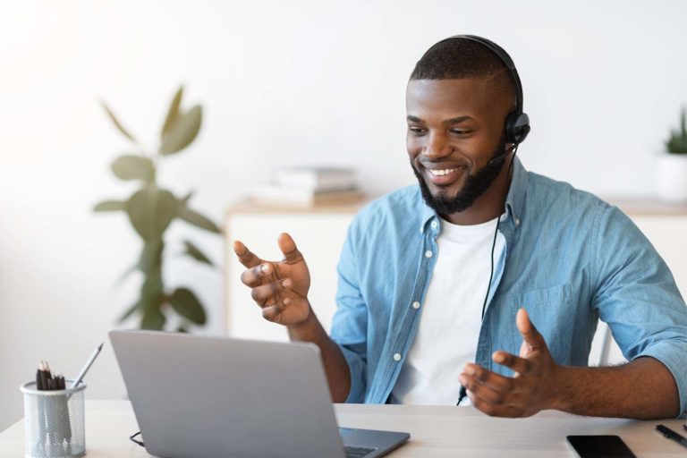 smiling male call center agent with headset talking on laptop