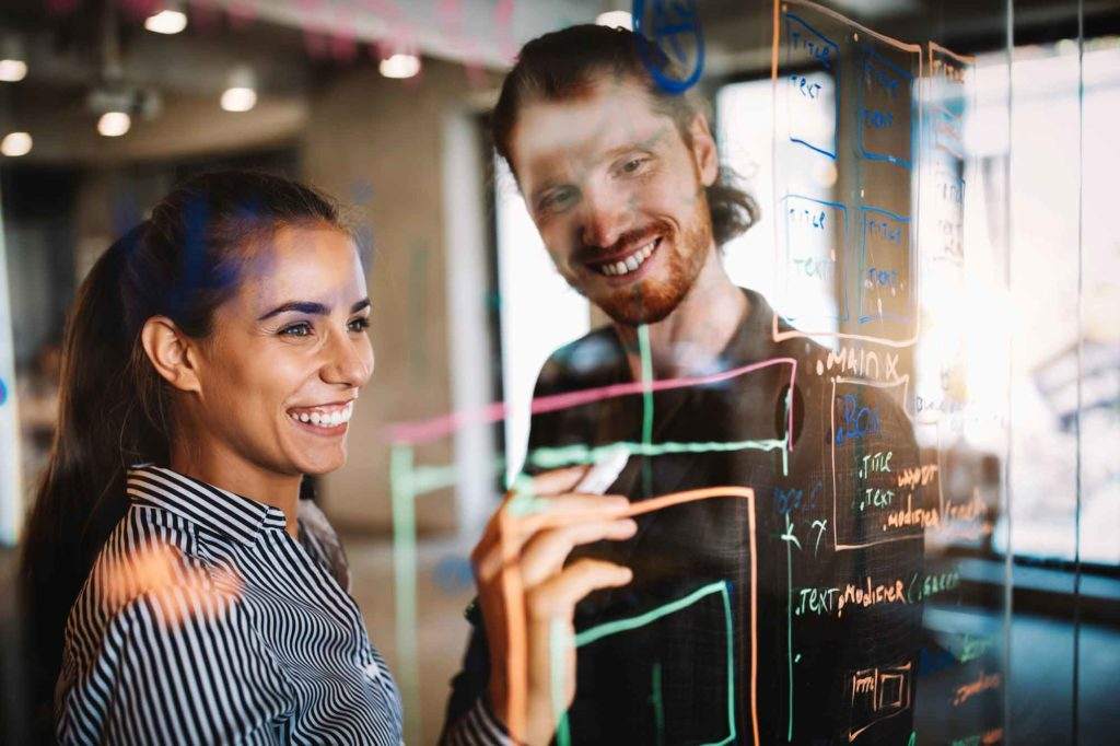 smiling employees writing on clear board