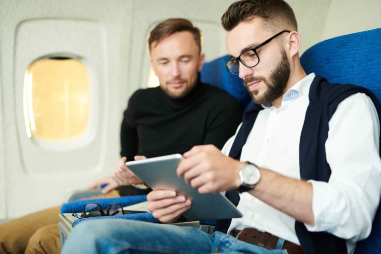 male passengers on airplane using tablet