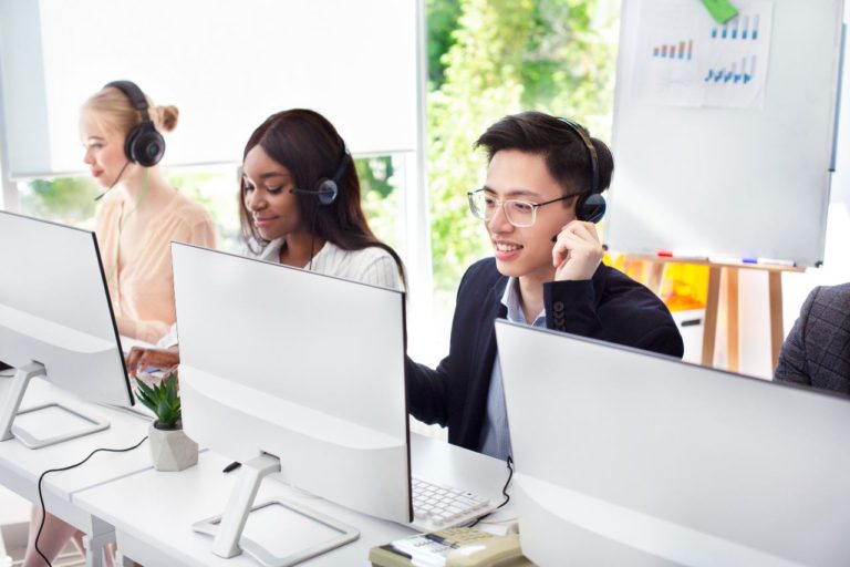 smiling call center agents talking on headsets in front of computers