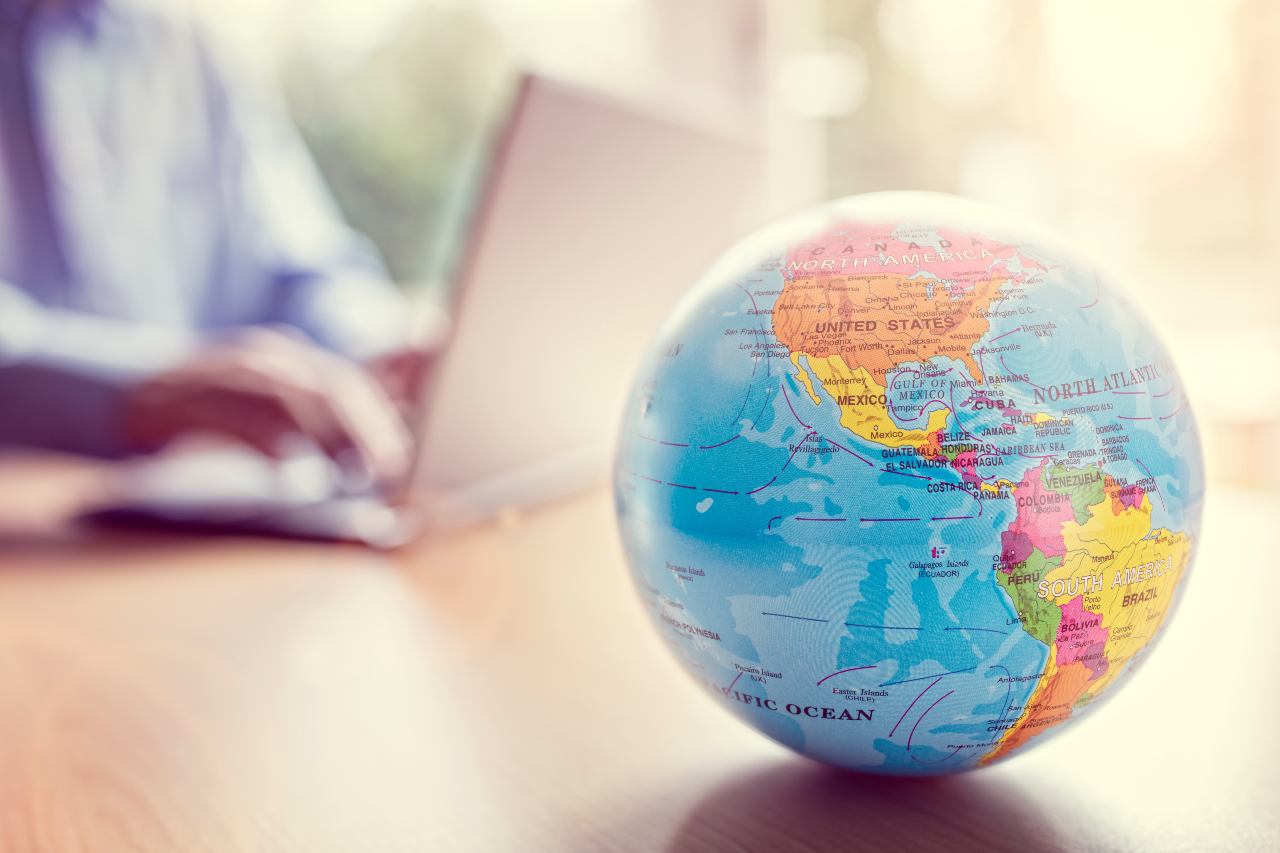 globe with business person typing on laptop in blurred background