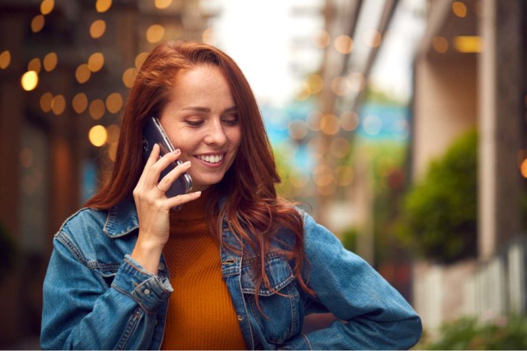 smiling female customer talking on the phone outdoors