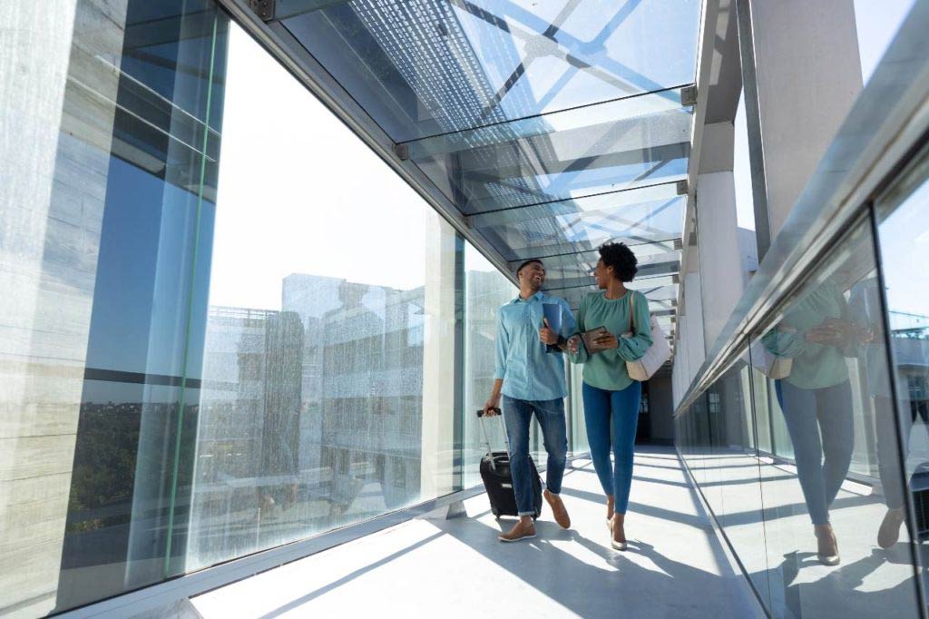 happy couple walking down airport corridor with luggage