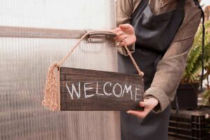 woman putting a handmade welcome sign on front door of business