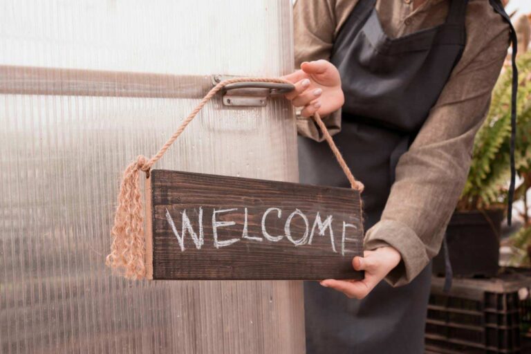 woman putting a handmade welcome sign on front door of business
