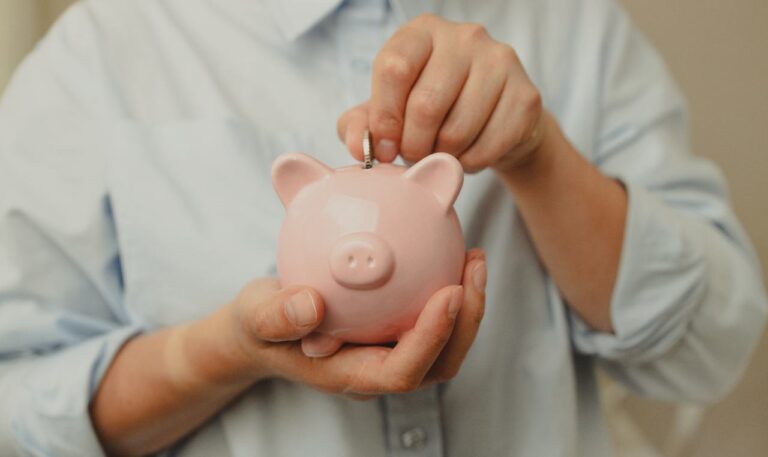 person depositing a coin into a piggy bank