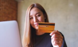smiling woman holding a credit card while on laptop