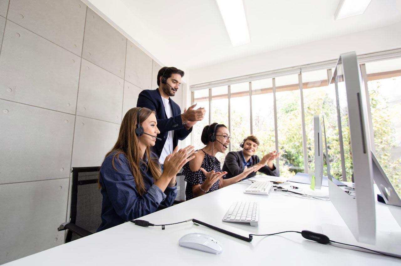 customer experience team celebrating in front of computers