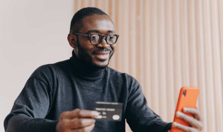 smiling financial services customer holding credit card and looking at smartphone