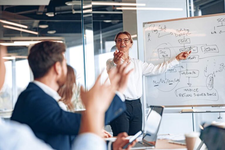 Experienced businesswoman by whiteboard explaining customer experience strategy at a meeting