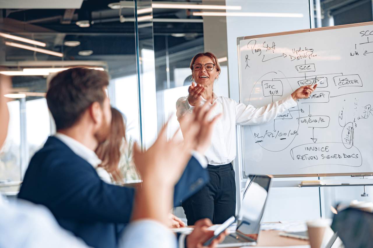 Experienced businesswoman by whiteboard explaining customer experience strategy at a meeting