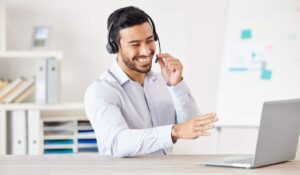 smiling customer service agent talking on headset with laptop open