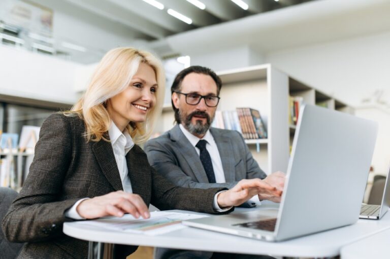 business associates smiling and looking at laptop