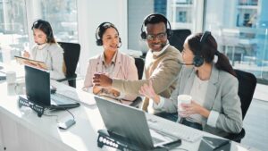Customer support team wearing headsets collaborates at desks in a bright office, illustrating outsourced call center support