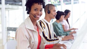 Customer service team members wearing headsets and working at computers in a modern contact center office